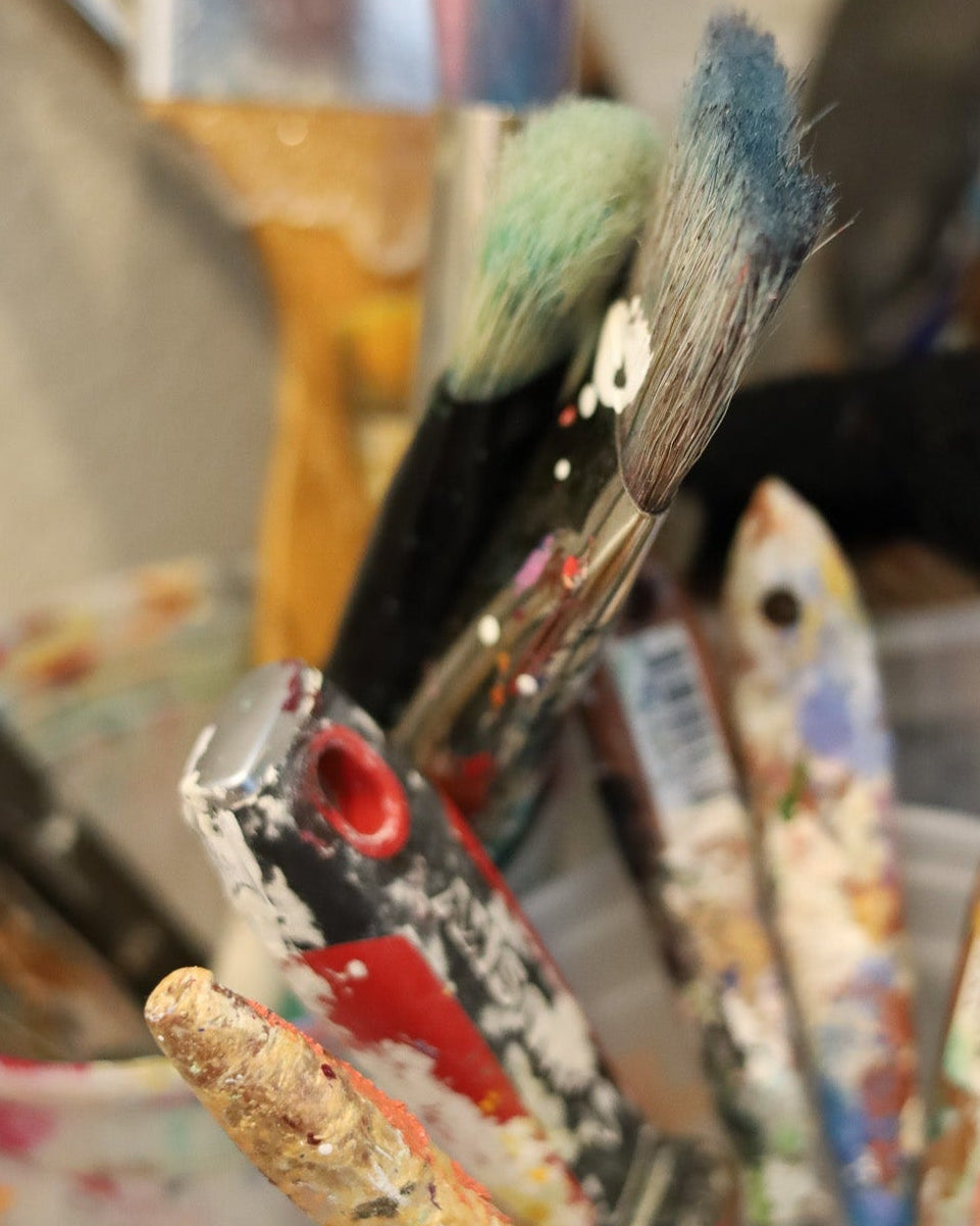 Collection of paintbrushes in a container with various colors and uses.